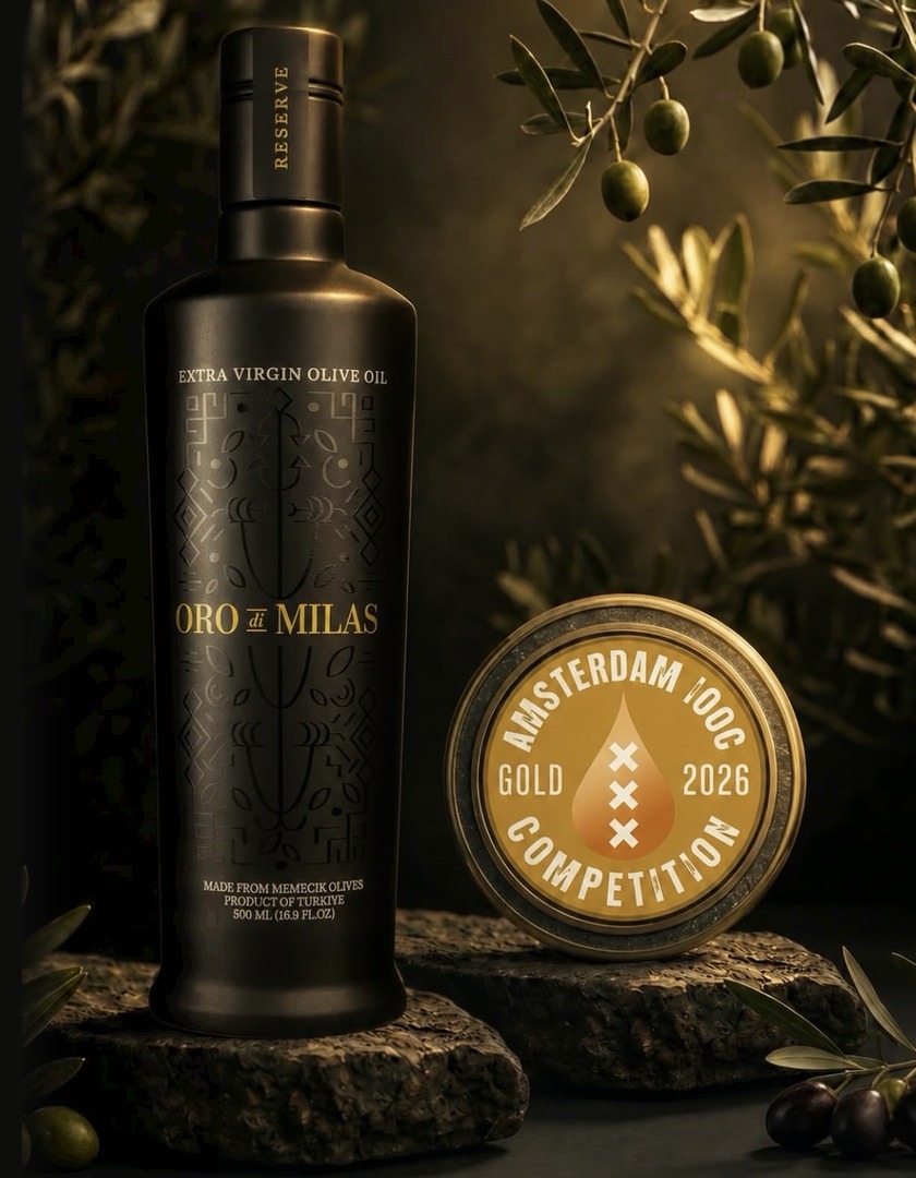 Oro di Milas Reserve Flasche neben der goldenen Amsterdam IOOC 2026 Medaille auf Naturstein unter Olivenzweigen