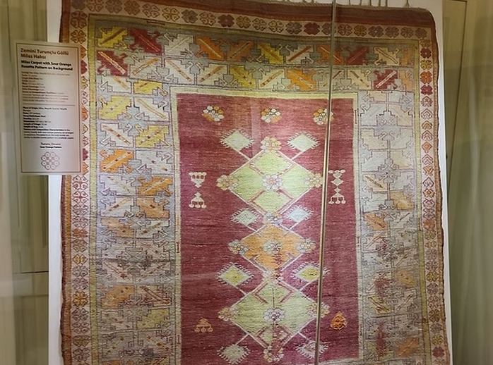 Traditioneller historischer Milas-Teppich im Museum mit geometrischen Rosetten-Ornamenten